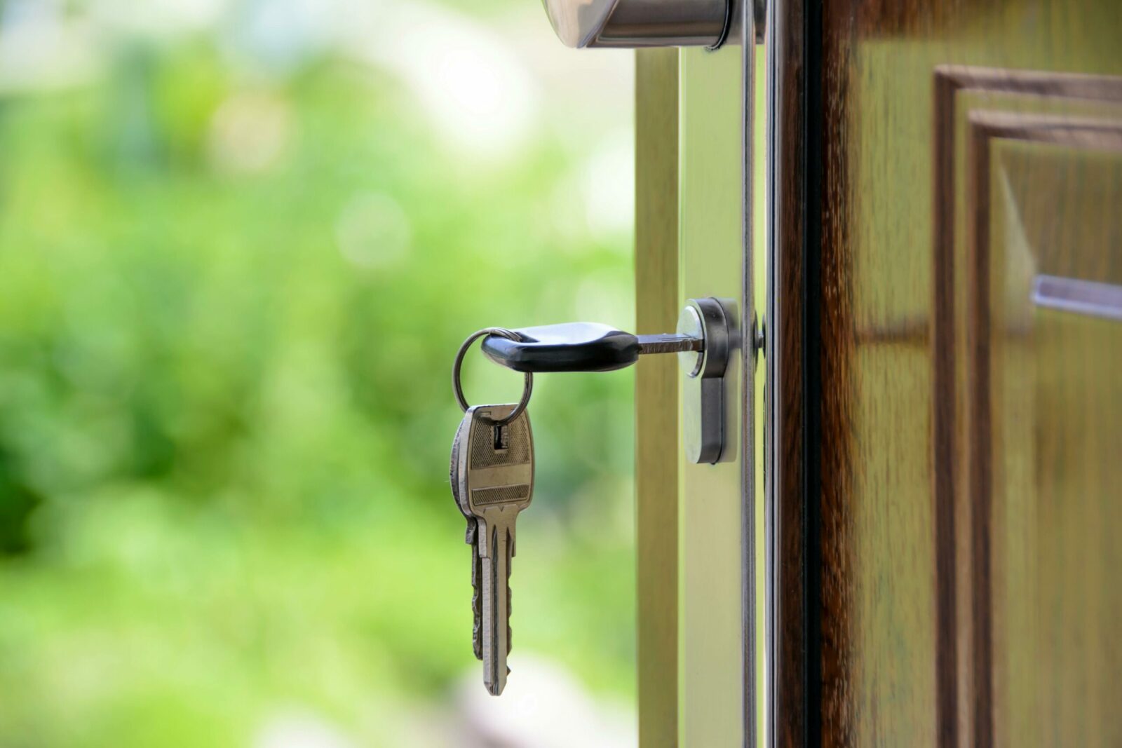 Photo by AS Photography - Czyste Powietrze - Audyty Key inserted in door lock against a blurred green background, symbolizing security and real estate.
