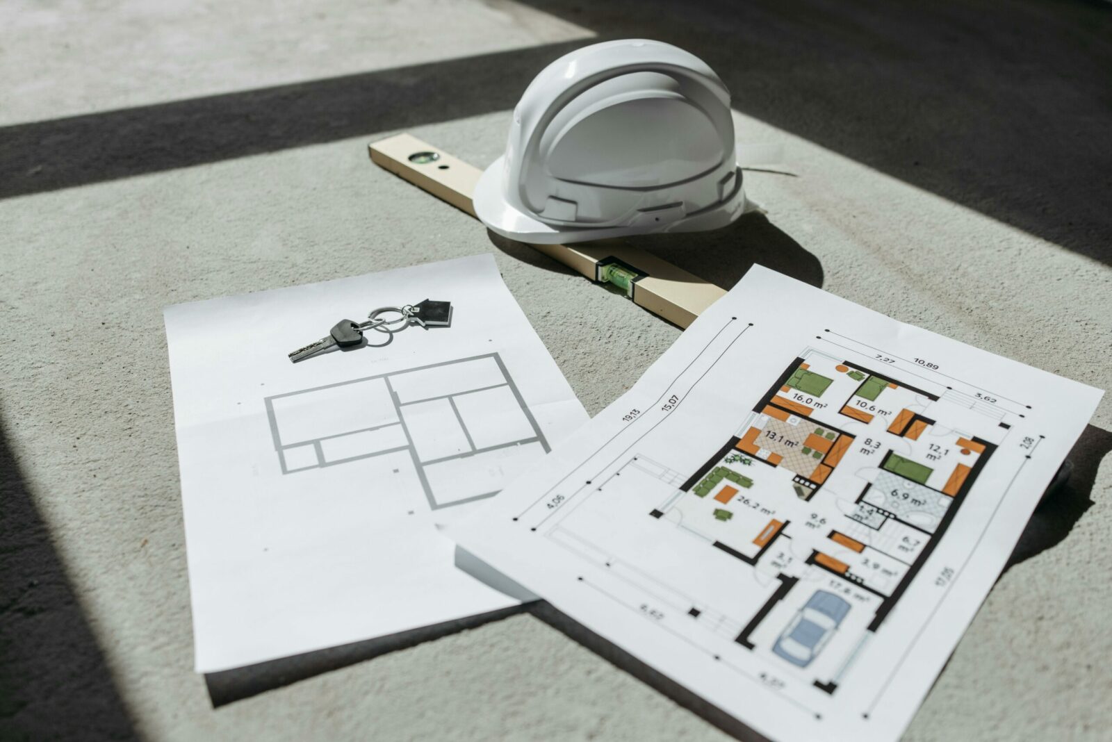 Photo by Pavel Danilyuk - Czyste Powietrze - Audyty Architectural floor plans with helmet and keys on sunlit floor, perfect for real estate or construction themes.